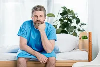 alargamiento_de_pene_paciente_sentado_bata_azul_rene_zamora_queretaro_200x133 Paciente en bata azul sentado en cama médica, representando tratamiento de alargamiento de pene en entorno clínico.